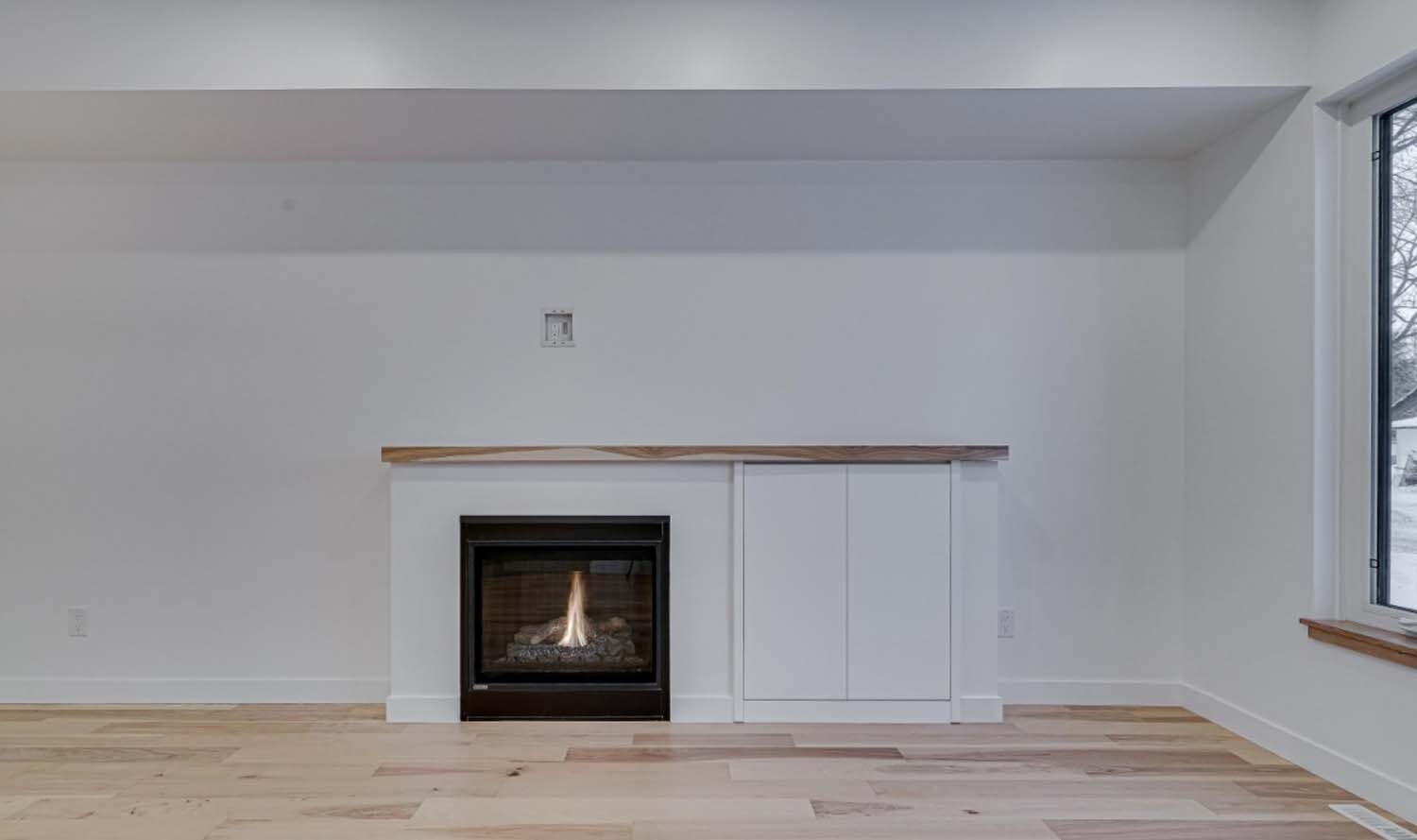 White fireplace with wood mantel and cabinet