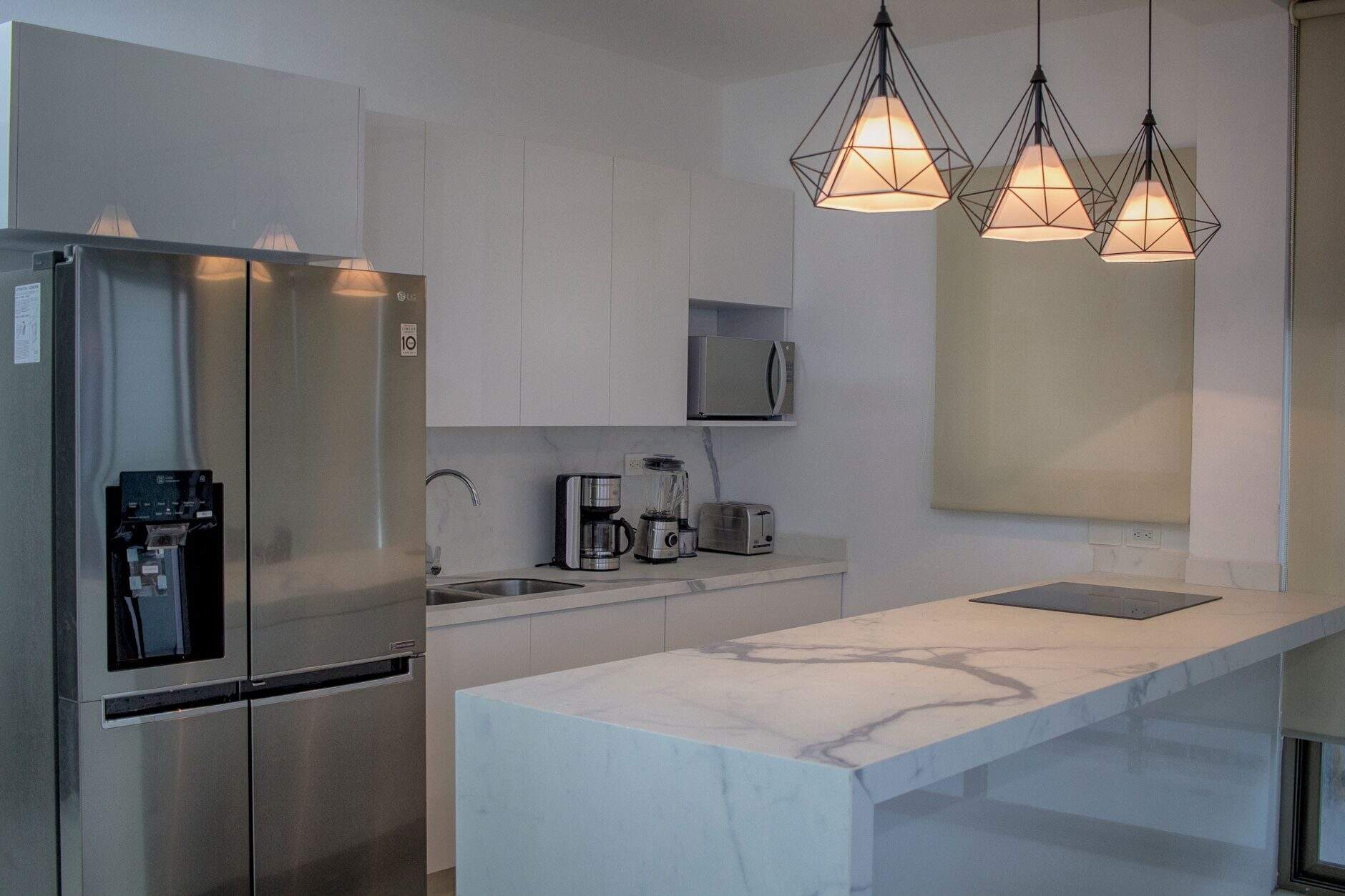 Modern kitchen renovation with white cabinetry, marble-style island, and pendant lighting